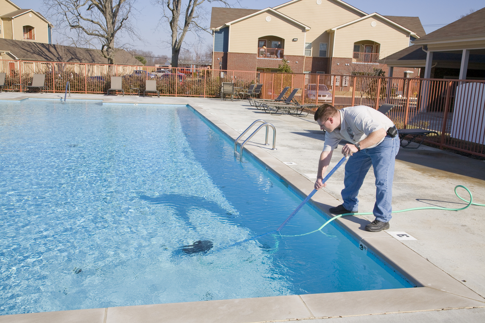 Man using an automatic pool brush/vacuum to clean the pool.
